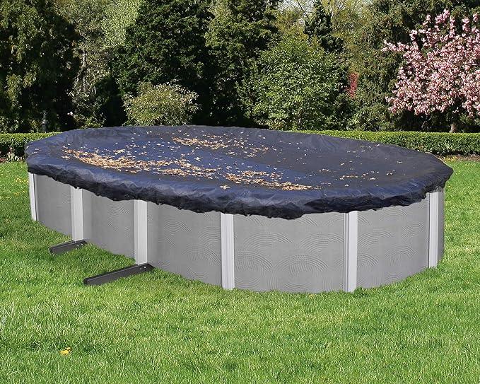 Piscine hors sol ovale avec bâche de protection noire sur pelouse, feuilles sur la bâche