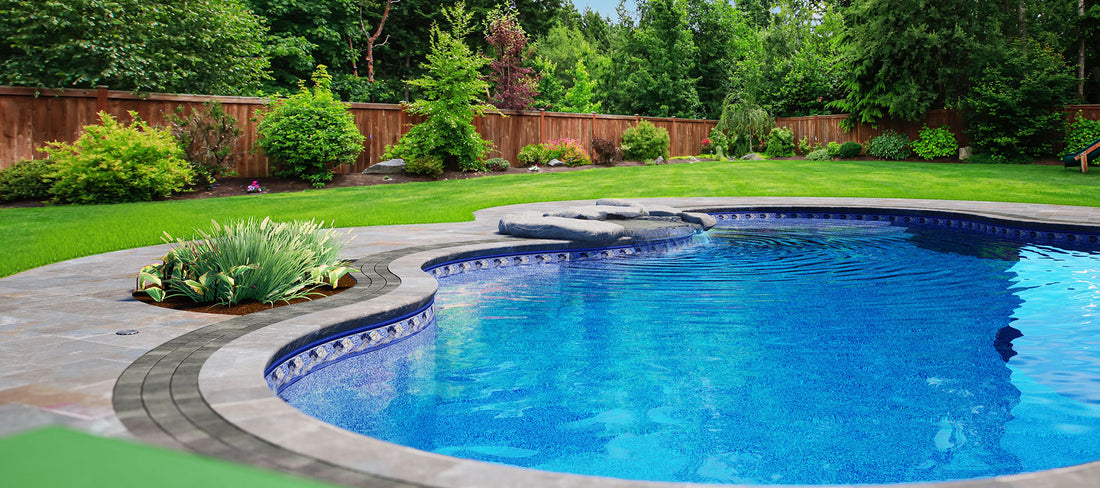Piscine creusée moderne avec margelle en pierre, cascade et jardin paysager